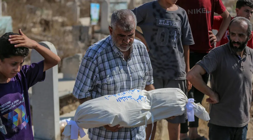 أقارب فلسطينيون من عائلة المصري يحيون مراسم دفنهم في مقبرة بمدينة غزة (إ.ب.أ)