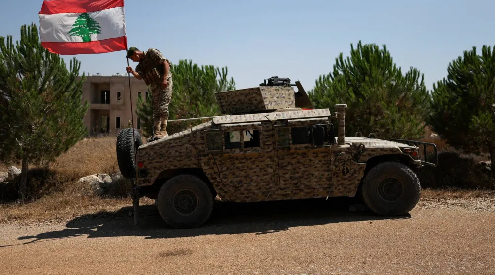 يرفع أحد الجنود اللبنانيين العلم اللبناني على آلية مدرعة في بلدة زوطر الغربية بجنوب لبنان بالتزامن مع انتشار وحدات الجيش في المنطقة عقب انسحاب القوات الإسرائيلية ضمن المرحلة الأولى من تنفيذ الخطة المدعومة أميركياً (رويترز)