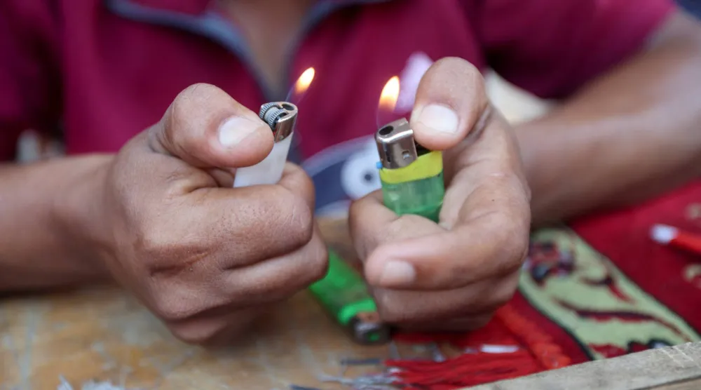 الفلسطيني حسن أبو لطيفة يشعل قدّاحة أصلحها في كشكه في ظل نقص الولاعات وغاز الطهي في خان يونس بجنوب قطاع غزة (رويترز)