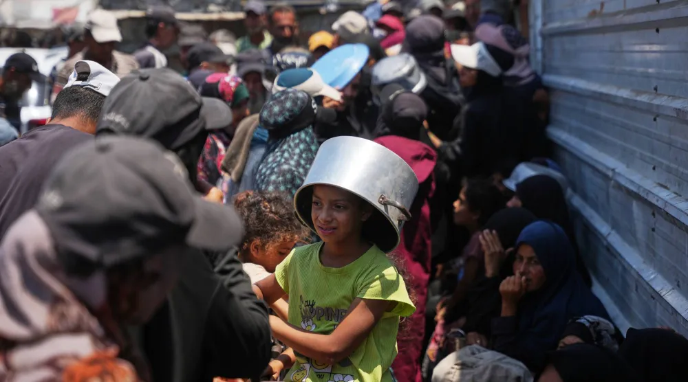 فلسطينيون نازحون يصطفون لتلقّي الطعام المتبرع به في مطبخ مجتمعي بخان يونس جنوب قطاع غزة 23 يوليو الحالي (أ.ب)