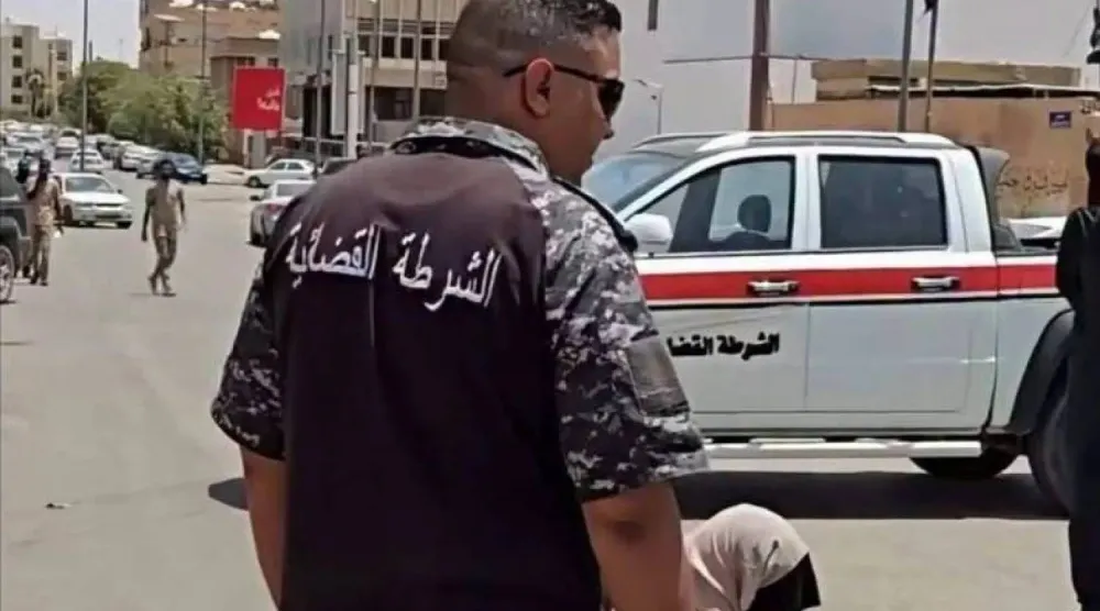 أحد أفراد الشرطة القضائية في مدينة سبها خلال تنفيذ حكم الجلد بحق المرأة المدانة (من مقطع فيديو)