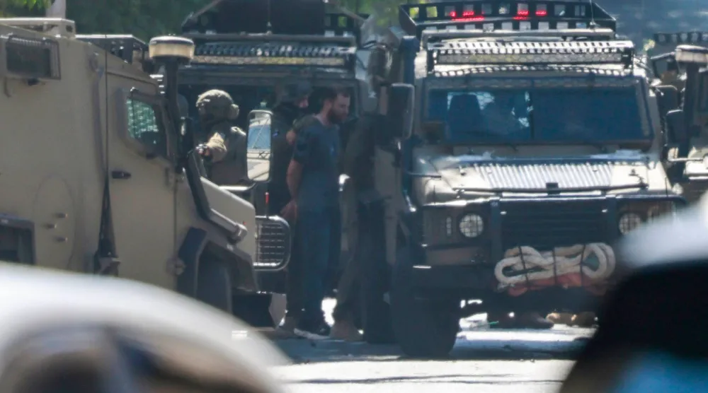 جنود إسرائيليون يعتقلون فلسطينياً في أثناء محاصرتهم مستشفى نابلس التخصصي في نابلس بالضفة الغربية المحتلة (أ.ف.ب)