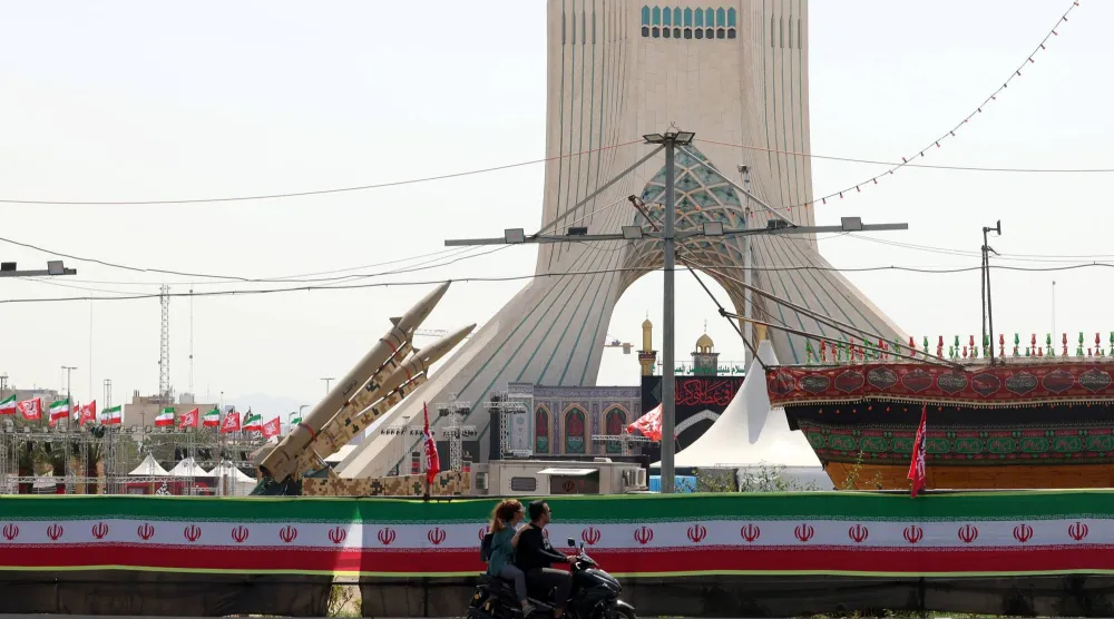 زوجان على دراجة نارية بجانب صواريخ إيرانية في ساحة آزادي بطهران (إ.ب.أ)