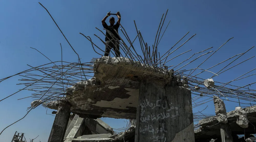 فلسطينيون يستخرجون الحديد من أنقاض المنازل التي دمَّرها الجيش الإسرائيلي خلال الحرب في خان يونس جنوب غزة (د.ب.أ)