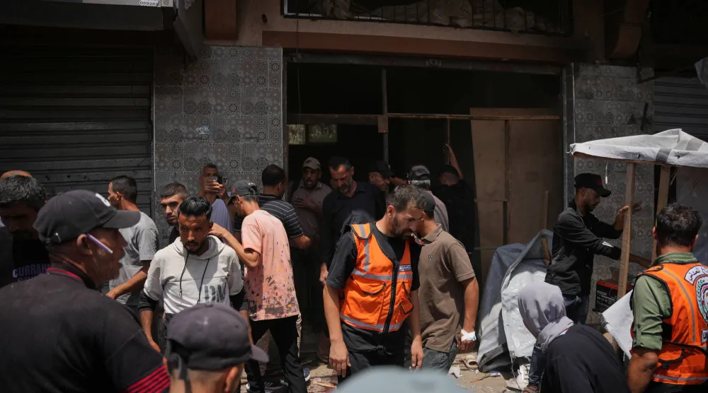 فلسطينيون يتفقدون موقع غارة عسكرية إسرائيلية في دير البلح، وسط قطاع غزة (أ.ب)