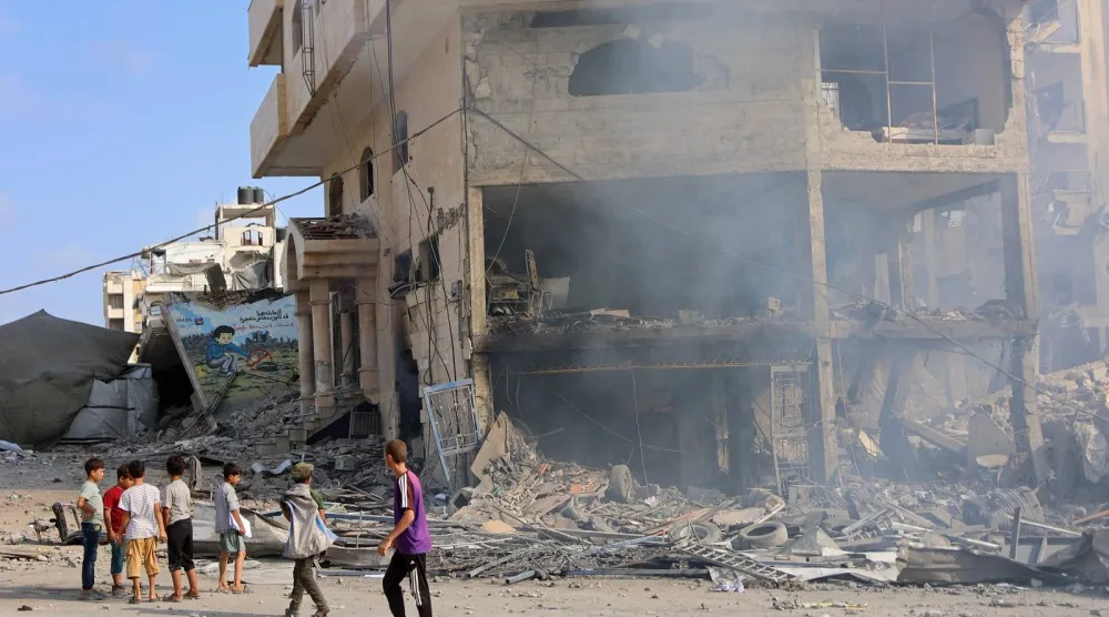 أطفال فلسطينيون يقفون بجوار مبنى مدمر في شارع الجلاء عقب غارة إسرائيلية في مدينة غزة (أ.ف.ب)