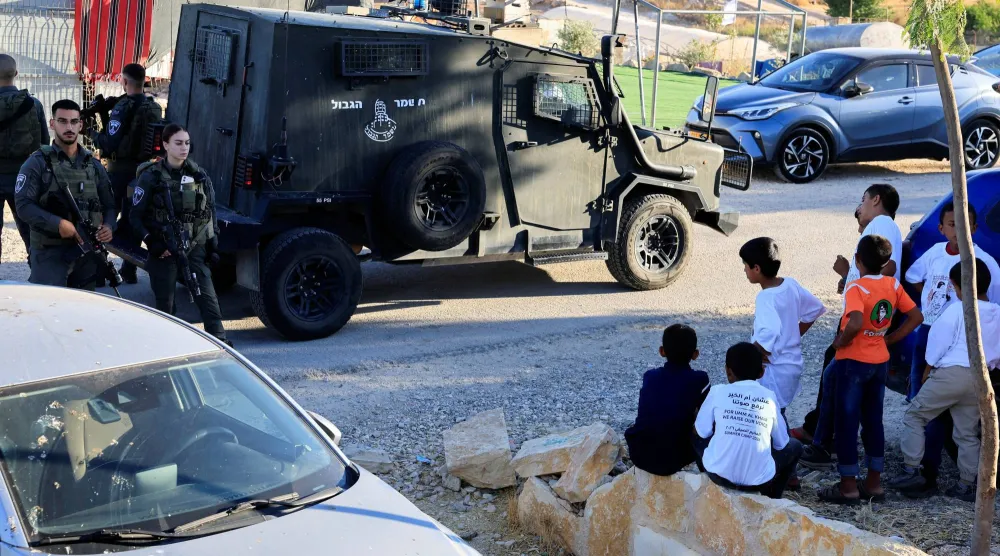 ينظر فتيان فلسطينيون إلى شرطة الحدود الإسرائيلية في أم الخير بالضفة الغربية المحتلة (رويترز)