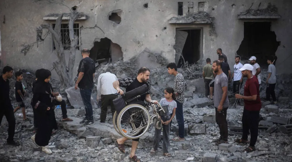 فلسطينيون يتفقدون يوم الأربعاء مباني تضررت ودُمرت جراء غارات إسرائيلية شُنّت الليلة السابقة في دير البلح بوسط غزة (أ.ف.ب)