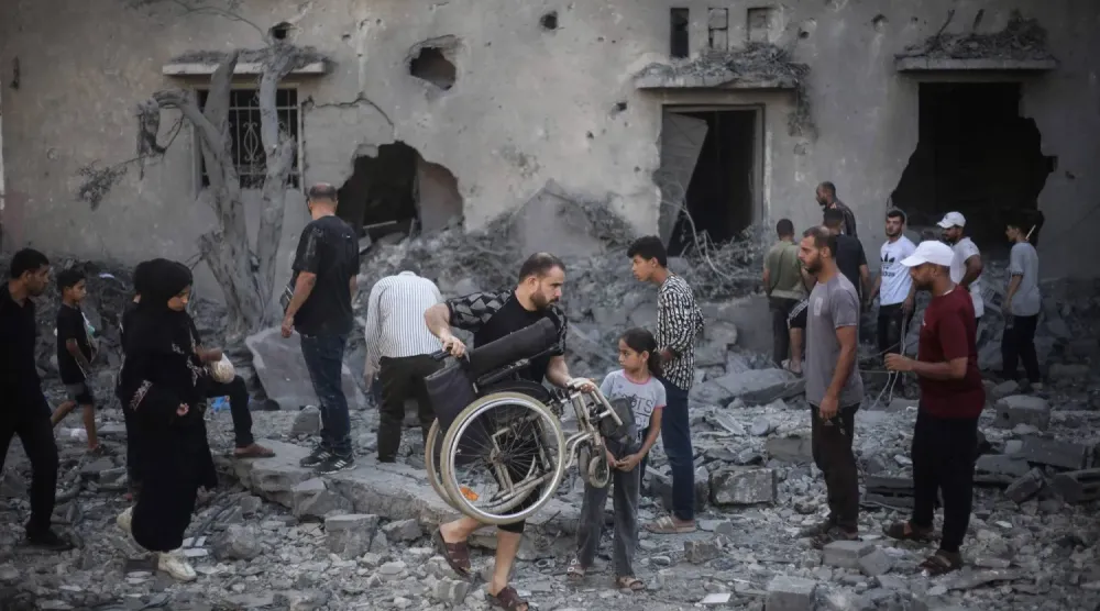 Gazze Şeridi’nin orta kesimindeki Deyr el-Balah’ta bir önceki gece İsrail hava saldırıları sonucu hasar gören ve yıkılan binaları inceleyen Filistinliler (AFP)
