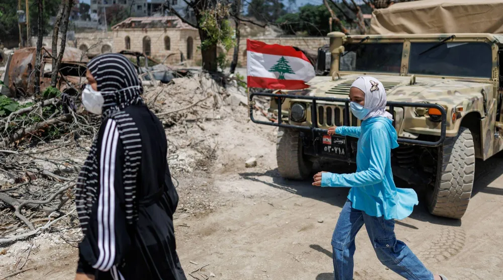 مواطنتان تمران أمام آلية عسكرية للجيش اللبناني أثناء انتشار الجيش بالمنطقة التجريبية الأولى في زوطر الغربية (رويترز)