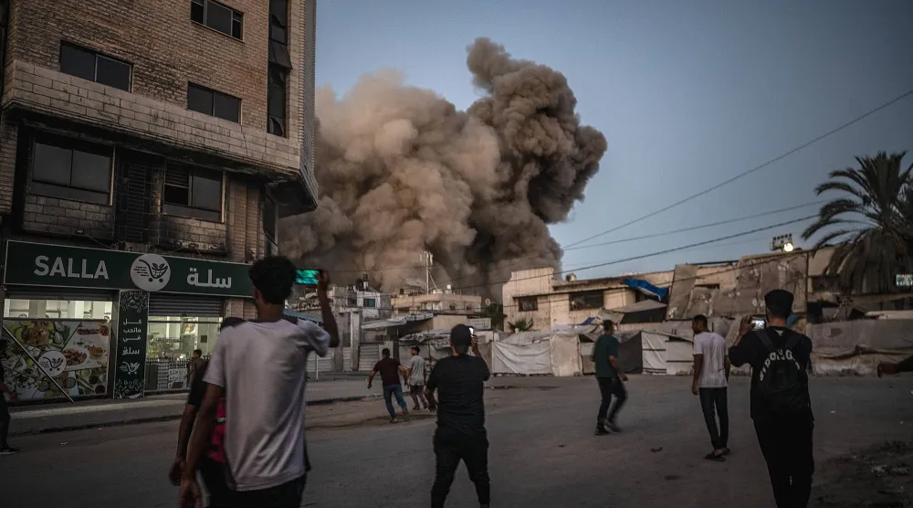 فلسطينيون يشاهدون قصفاً إسرائيلياً استهدف قطاع غزة (إ.ب.أ)