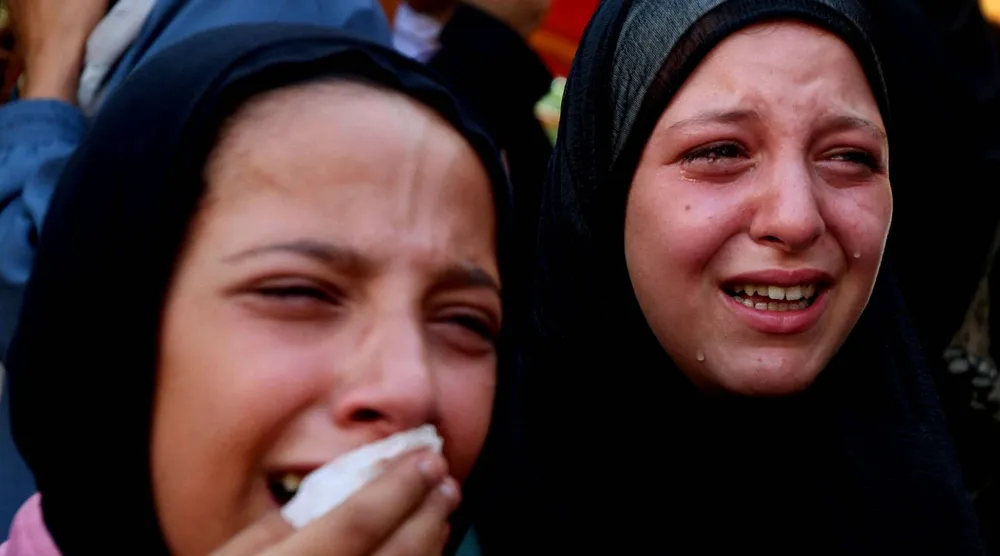  فتاتان تنتحبان أمس خلال جنازة فلسطينيين قُتلوا في غارات إسرائيلية استهدفت خياماً في خان يونس جنوب غزة (رويترز)