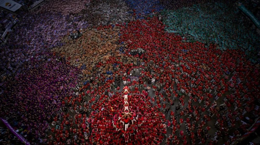 Castells geleneğinde kulenin en tepesine çıkan enxaneta, elini havaya kaldırarak insan kulesinin tamamlandığını gösteriyor (AP)