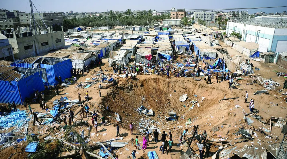 
فلسطينيون يعاينون مكاناً استهدفته ضربة جوية إسرائيلية قرب مستشفى الأقصى بدير البلح وسط قطاع غزة أمس (أ.ب)