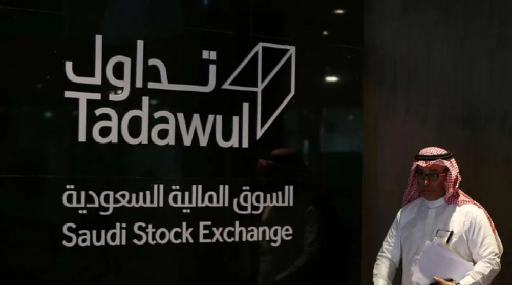رجل يعبر أمام شعار «تداول» السعودية (أ.ف.ب)