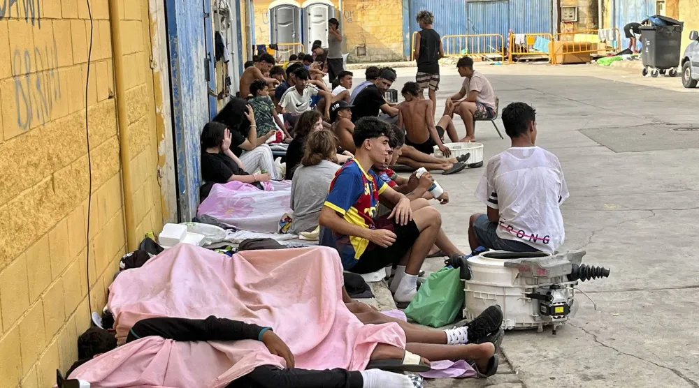 مهاجرون دخلوا سبتة سباحةً أو سيراً على الأقدام من المغرب يجلسون في أحد شوارع سبتة بإسبانيا (إ.ب.أ)