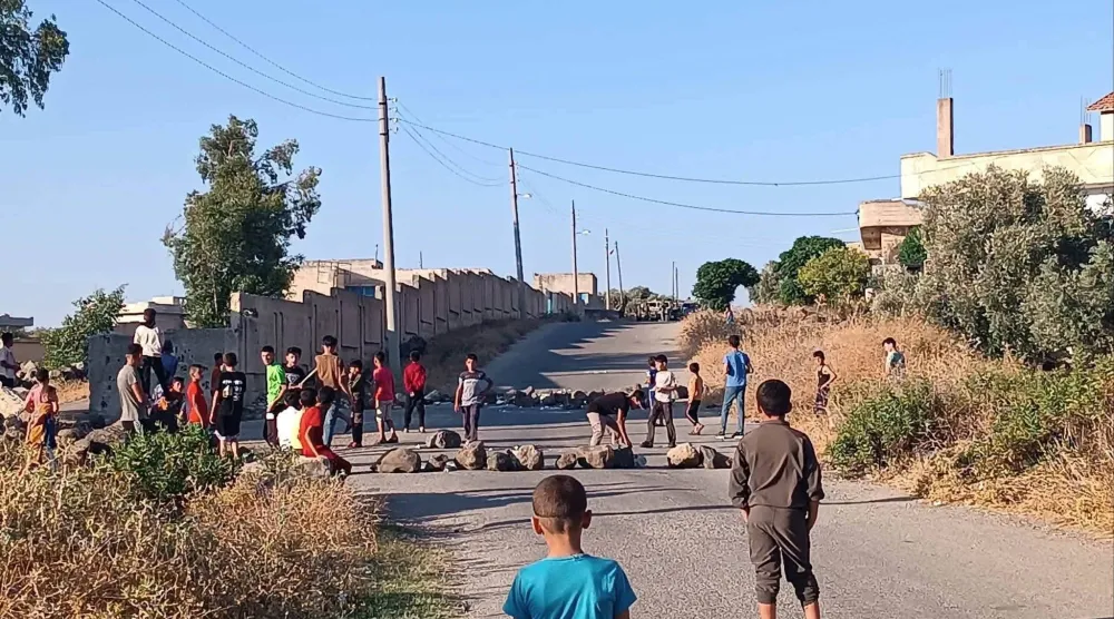 أطفال يغلقون الطريق في قرية عابدين بمنطقة حوض اليرموك بريف درعا الغربي جنوب سوريا في محاولة لمنع دوريات الجيش الإسرائيلي من التوغل في القرية (فيسبوك)
