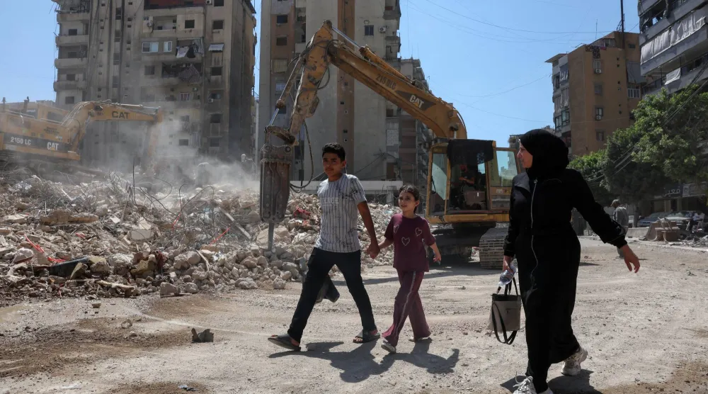 People walk past the rubble of buildings damaged in Israeli strikes in Beirut’s southern suburbs, following a ceasefire agreement between Lebanon and Israel, in Beirut, Lebanon, July 6, 2026. REUTERS/Mohamed Azakir