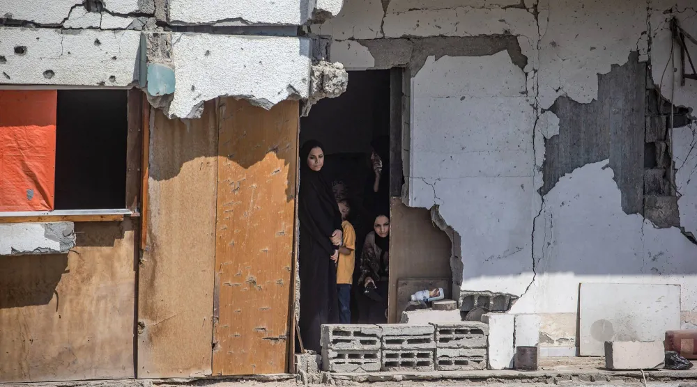 فلسطينيون يشاهدون جنازة 112 من أفراد عشيرتهم شرق مدينة غزة بعد انتشالهم من تحت أنقاض مباني دمرت في 2023 (إ.ب.أ)