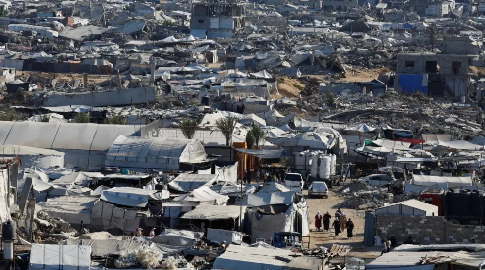 فلسطينيون يسيرون وسط أنقاض مبانٍ سكنية دُمّرت خلال الحرب في مخيم جباليا للاجئين شمال قطاع غزة (رويترز)