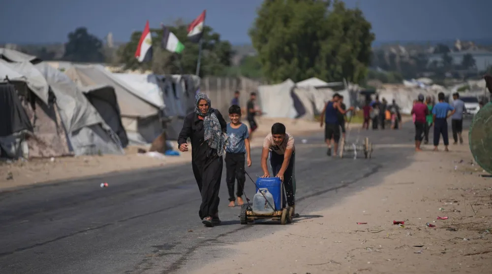 ينقلون الماء بأوعية على عربة في مخيم للنازحين في دير البلح وسط قطاع غزة الجمعة (أ.ب)