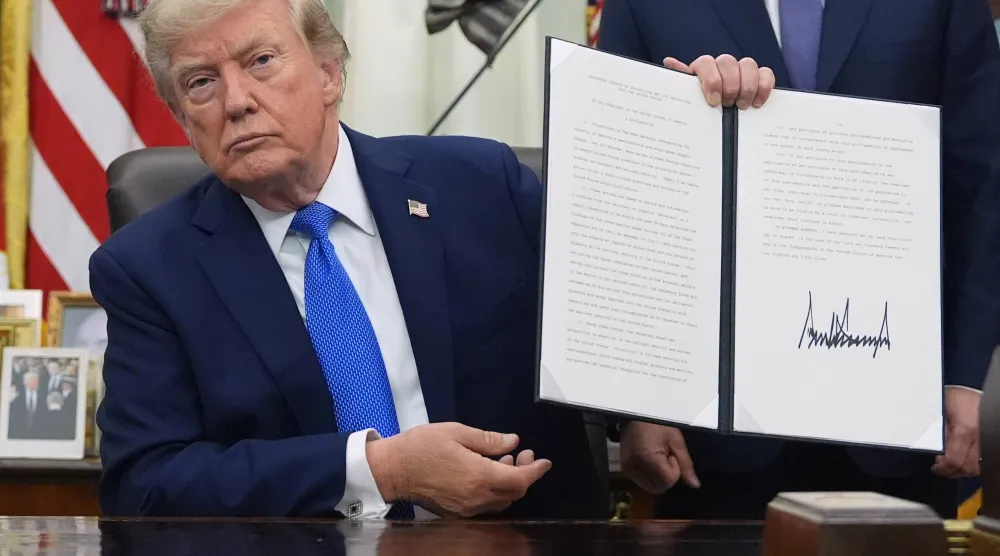 الرئيس الأميركي دونالد ترمب يرفع قراراً تنفيذياً في البيت الأبيض يوم 6 أغسطس (أ.ب)