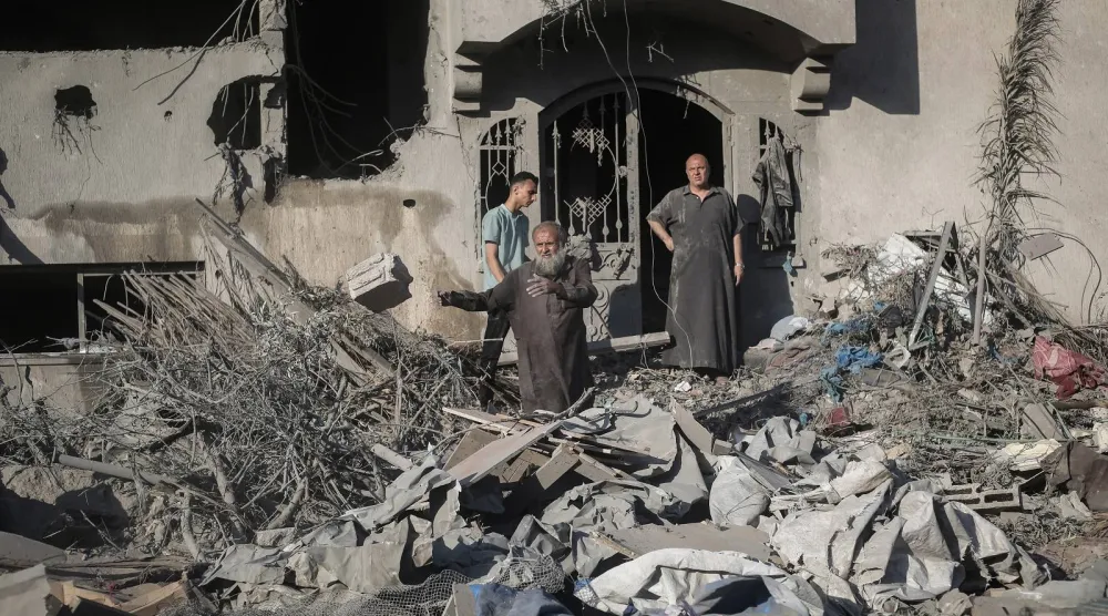فلسطينيون يتفقدون مباني متضررة بعد استهدافها بضربات إسرائيلية في دير البلح (أ.ف.ب)
