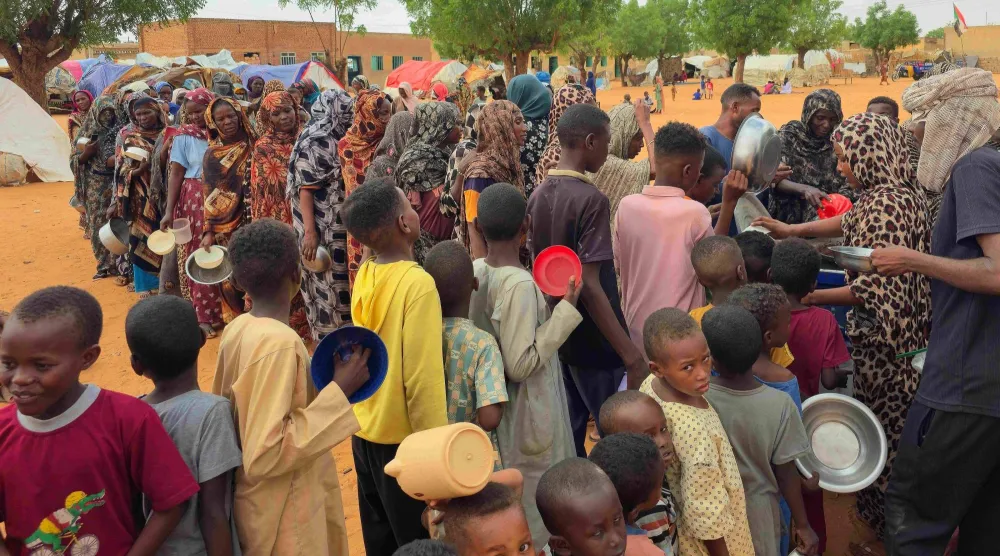نساء وأطفال في طوابير لتلقي مساعدات غذائية مجانية تُوزع في مخيم المحيرة للنازحين قرب مدينة الأُبيّض بمنطقة جنوب كردفان في السودان يوم 29 يونيو 2026 (أ.ف.ب)