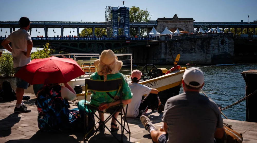 Spectators watch an athlete compete in the men's 20m high diving event during the LEN European Aquatics Championships, alongside the Seine River, in Paris on August 7, 2026. (AFP)