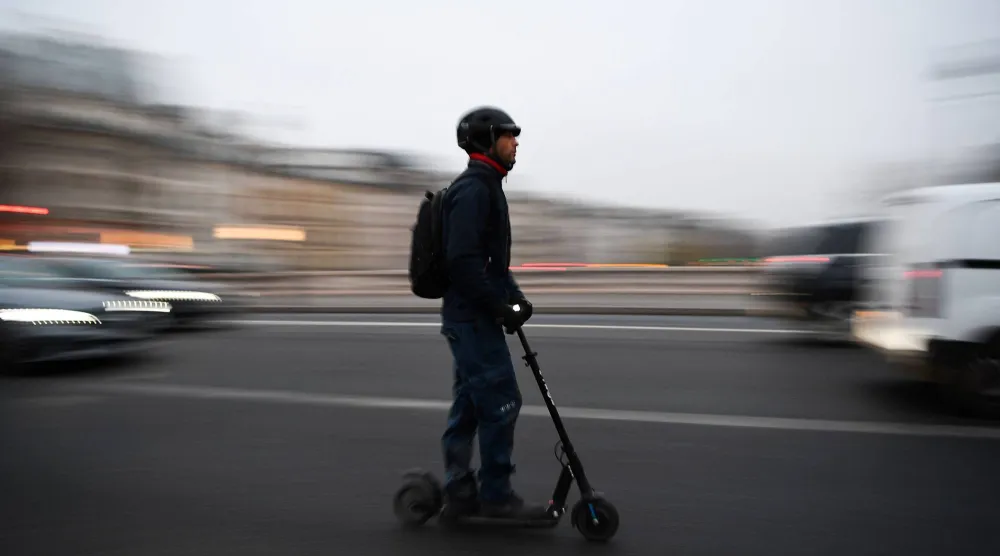 (FILES) A man rides an electric scooter past traffic on a street of Paris on December 5, 2019. (Photo by CHRISTOPHE ARCHAMBAULT / AFP)