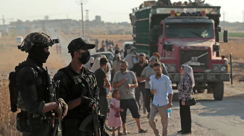 عناصر أمن يتابعون عودة أكراد سوريين في مخيمات نزوح بالحسكة إلى مدينة رأس العين الحدودية الشمالية الشرقية (أ.ف.ب)