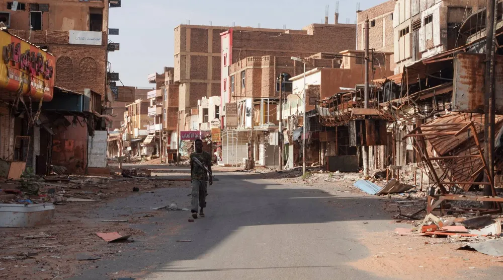 أحد أفراد الجيش السوداني يمرّ بين منازل متضررة جراء الحرب بالخرطوم (أرشيفية-رويترز)