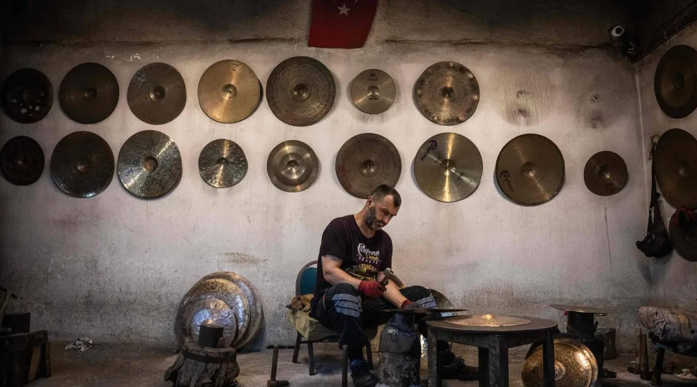 A worker hammers a cymbal at a workshop in Istanbul on July 30, 2026. (AFP) 