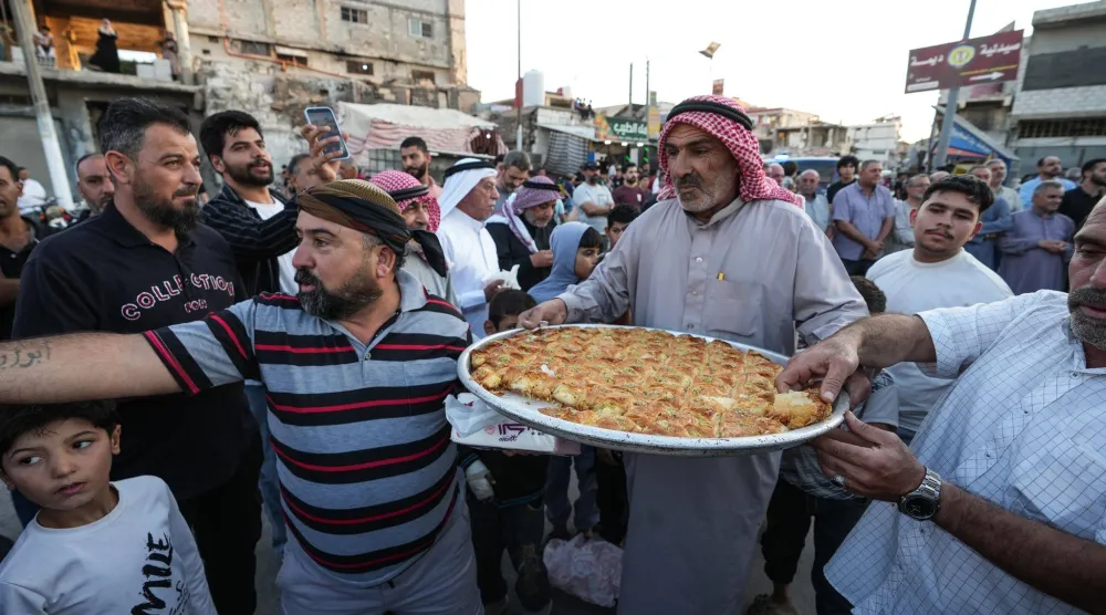 سوريون يوزّعون الحلويات خارج المسجد العمري في درعا البلد احتفالاً بالحكم على عاطف نجيب رجل أمن الأسد الذي ارتكب جرائم بحق الأهالي (د.ب.أ)