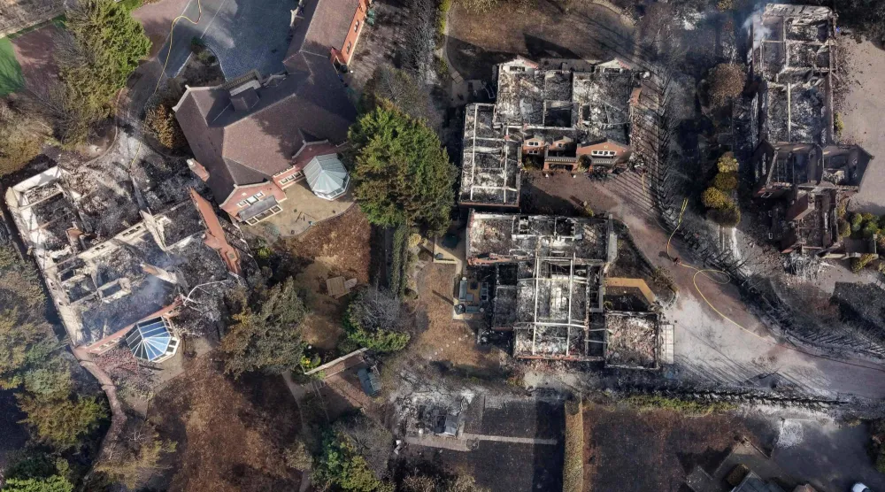 An aerial view shows smoke rising from fire-damaged houses, south of Stourbridge town center in central England on August 14, 2026. (Photo by Darren Staples / AFP)