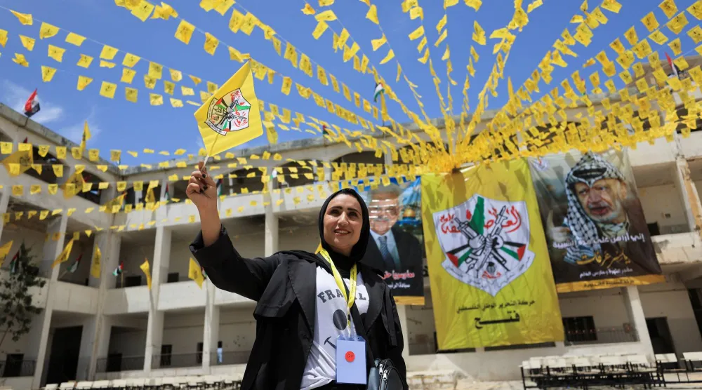 فلسطينية تلوّح بعَلم «فتح» خلال مشاركتها بالمؤتمر الثامن للحركة في جامعة الأزهر بمدينة غزة 14 مايو 2026 (رويترز)