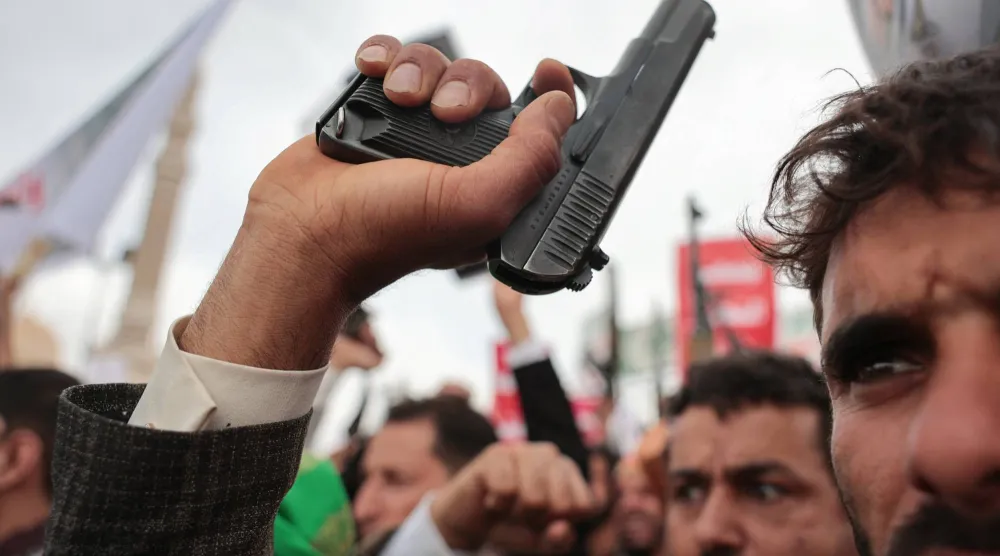 عنصر حوثي يرفع مسدساً خلال حشد للجماعة بصنعاء (رويترز)
