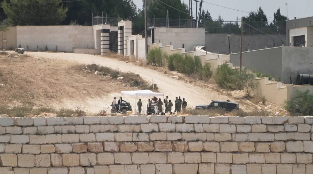 مستوطنون إسرائيليون أمام منازل فلسطينية محاصرة في قرية قصرة بالضفة الغربية المحتلة جنوب نابلس (أ.ب)