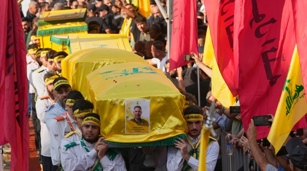 يحمل عناصر من كشافة «حزب الله» نعوش القيادي علي الحاج حسن وزوجته وأطفاله الأربعة الذين قُتلوا السبت في غارة إسرائيلية وذلك خلال موكب تشييعهم بالضاحية الجنوبية يوم الأحد (أ.ب)