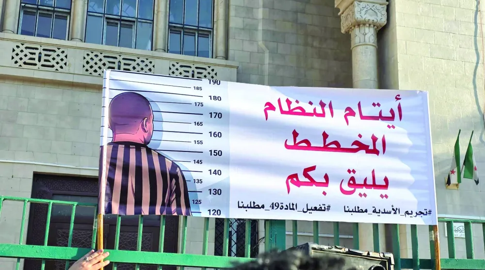 ناشطون أمام القصر العدلي بدمشق في يونيو الماضي يطالبون بتجريم رموز حقبة الأسد (فيسبوك)