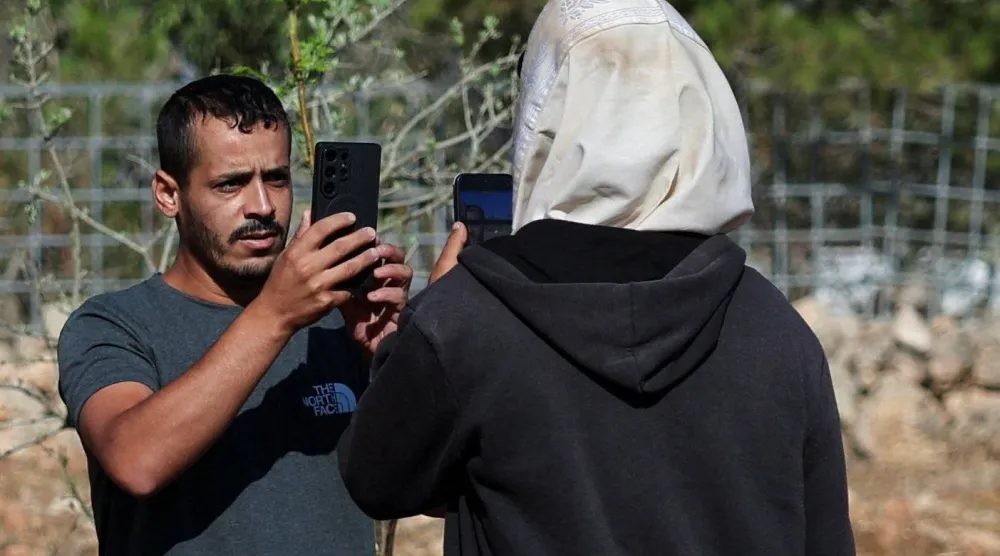 الفلسطيني - الأميركي لؤي أبو ​ريدة يصور مستوطناً داخل أرضه في قرية قصرة بالضفة الغربية المحتلة الثلاثاء (رويترز)