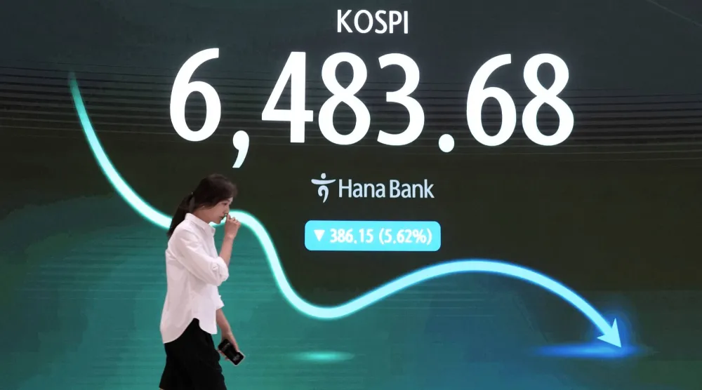 متداول يمر أمام شاشة تعرض مؤشر أسعار الأسهم الكوري المركب في غرفة تداول العملات الأجنبية بمقر بنك هانا (أ.ب)