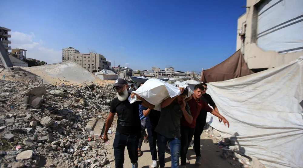 السكان يشيعون الفلسطينيين الذين سقطوا في غارة إسرائيلية على ميناء مدينة غزة الثلاثاء (د.ب.أ)