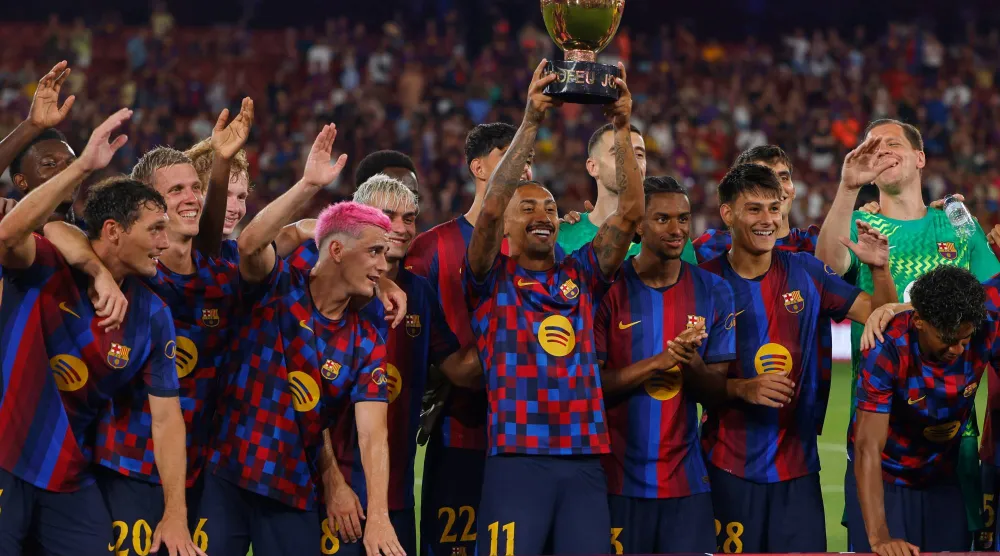 لاعبو برشلونة يحتفلون بالتتويج بكأس خوان غامبر عقب الفوز على الأهلي المصري في ملعب «كامب نو» (أ.ب)
