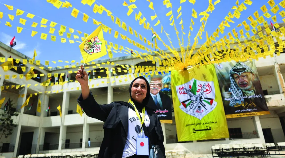فلسطينية تلوّح بعَلم «فتح» خلال مشاركتها في المؤتمر الثامن للحركة بجامعة الأزهر بمدينة غزة 14 مايو 2026 (رويترز)