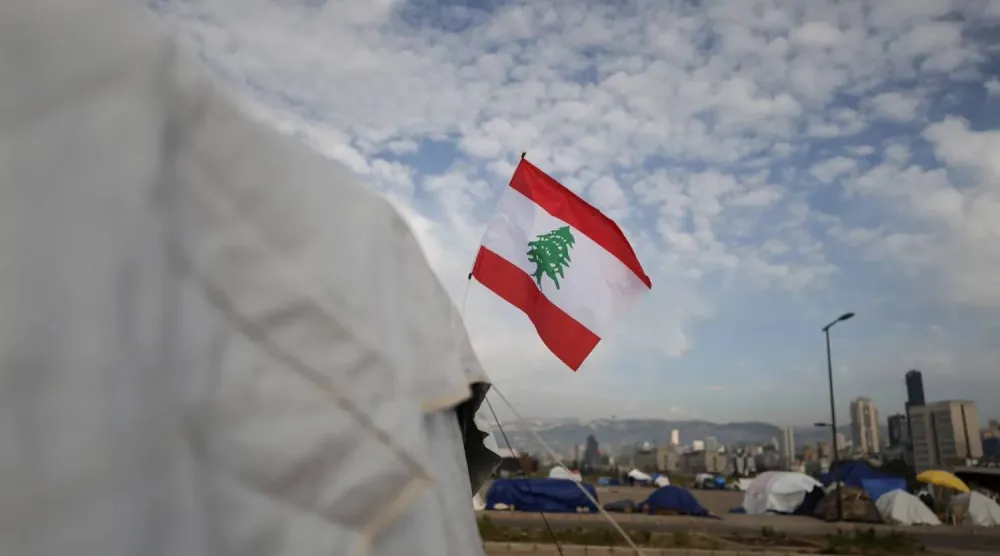 علم لبنان يرفرف على خيمة نازحين بمخيم مؤقت في بيروت (رويترز)
