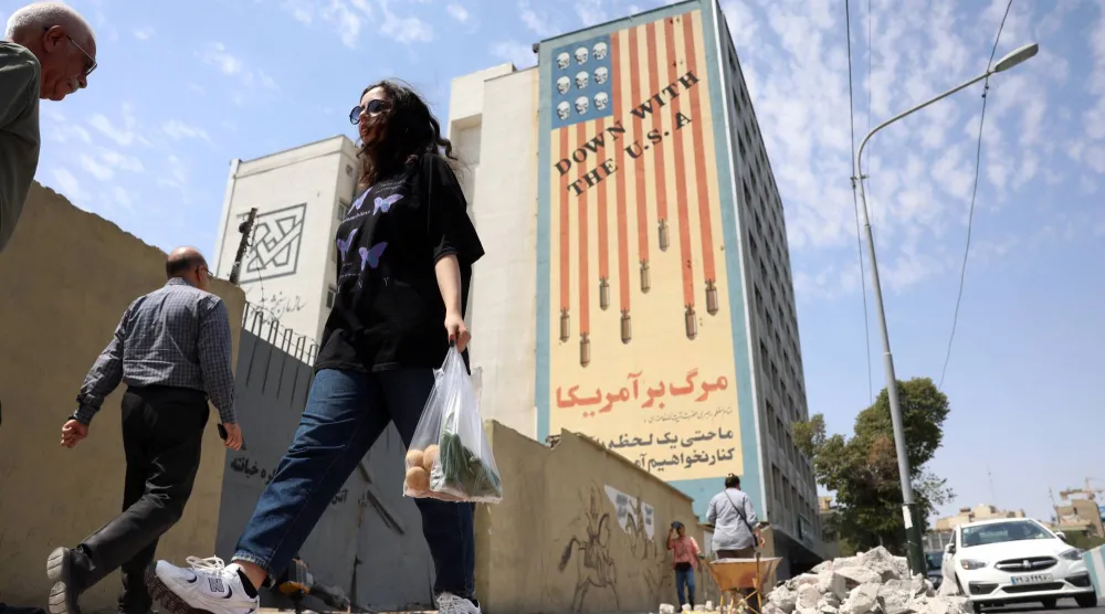 Iranian people walk past an anti-US mural in Tehran, Iran, 17 August 2026. (EPA)