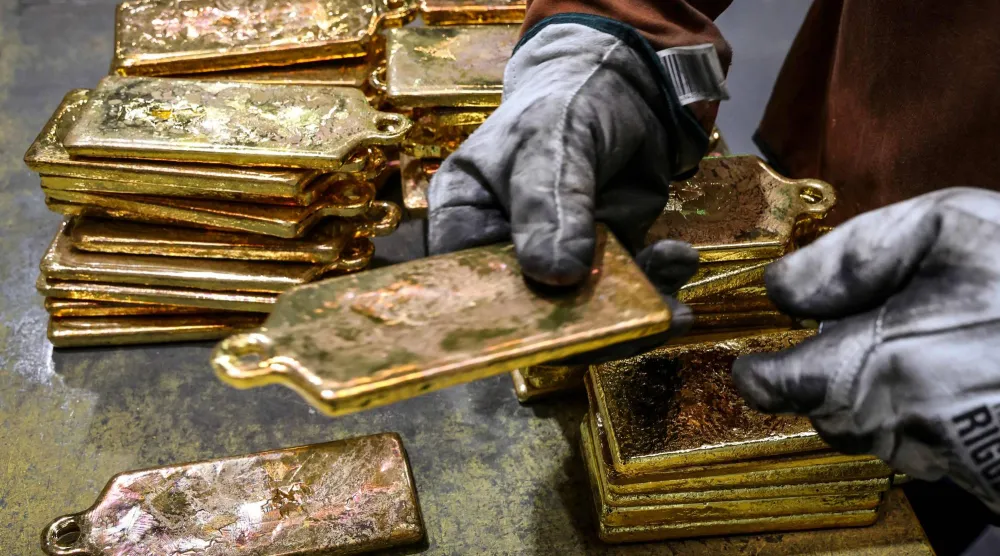 عامل مصفاة يقوم بتكديس سبائك الذهب بعد إخراجها من قوالبها في مصهر مصفاة في سيدني (أ.ف.ب)