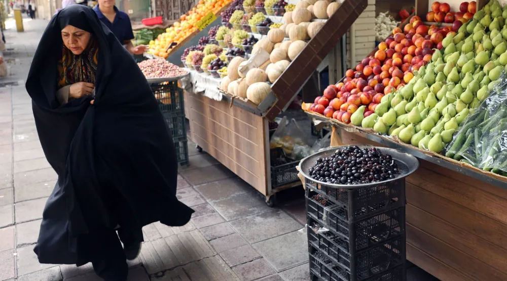 سيدة إيرانية تسير في إحدى الأسواق في طهران (إ.ب.أ)