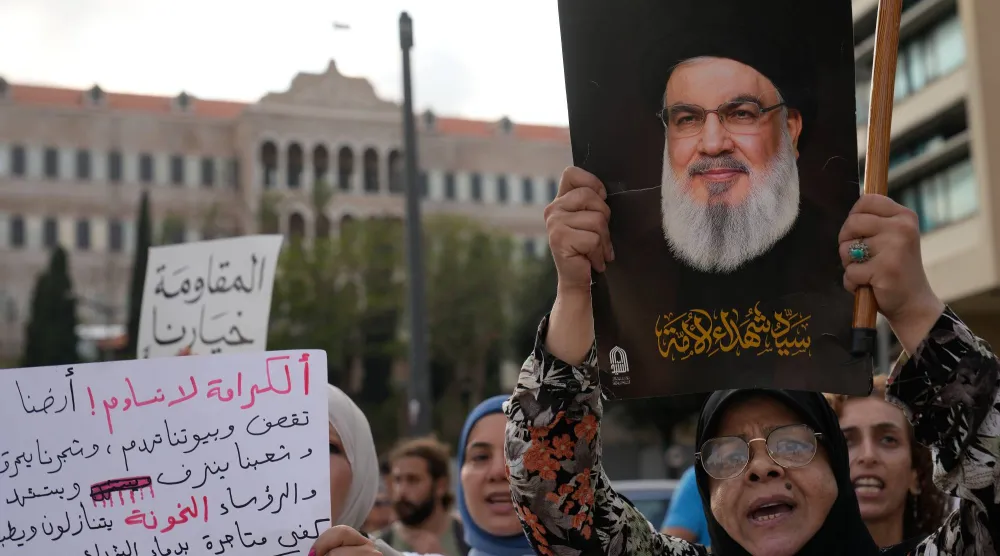 سيدة ترفع صورة أمين عام «حزب الله» السابق حسن نصر الله خلال احتجاج نظّمه الحزب رفضاً للمفاوضات اللبنانية مع إسرائيل (أ.ب)